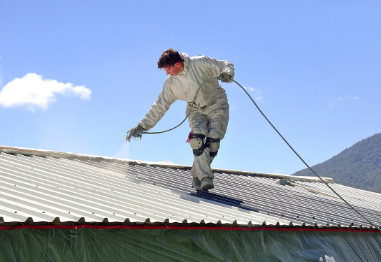 Man spraying coating on a cool roof.