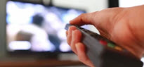 hand pointing a remote control at a TV