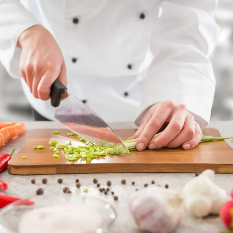 Chef cutting celery on a cutting board