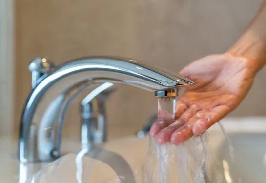 Hand under water running from faucet.